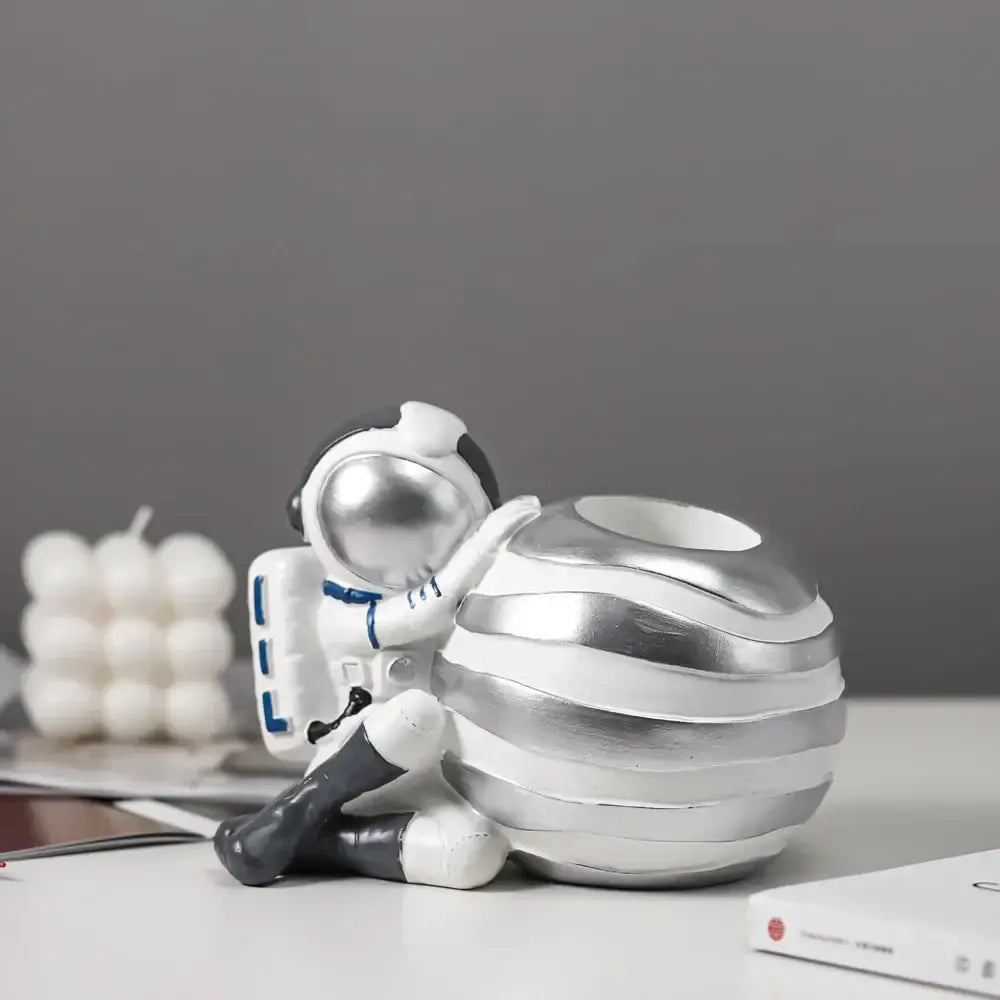 Modern white and blue decorbites astronaut resin figurines with silver accents sitting beside a striped planter