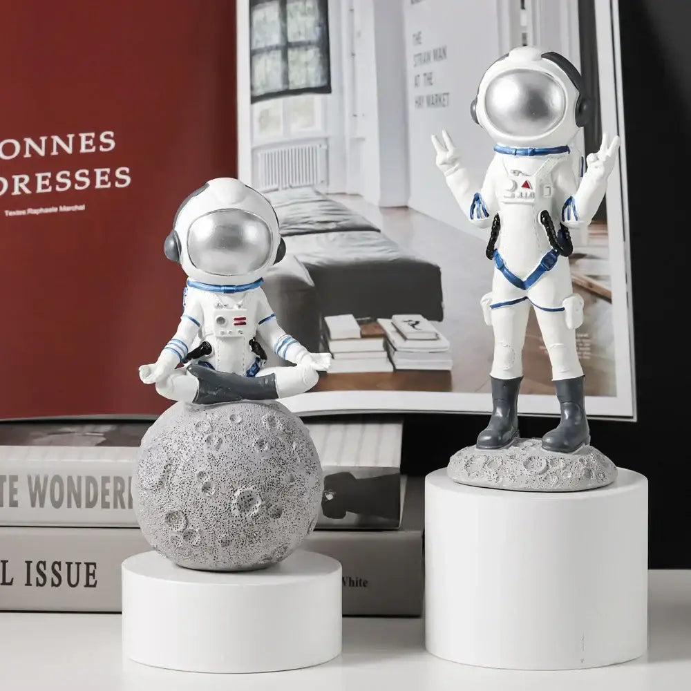 Modern white and blue astronaut resin figurines featuring silver helmets on a textured gray moonbase for living room decorbites astronaut resin decor