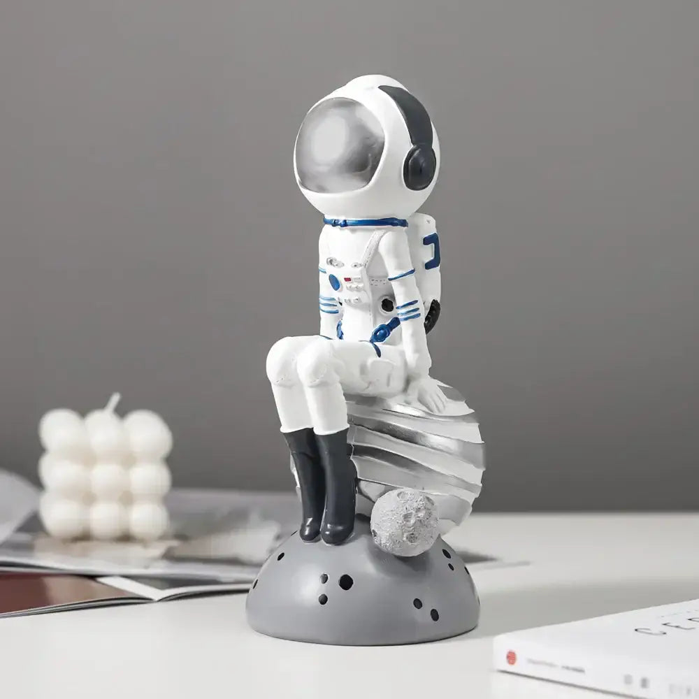 Modern white and blue decorbites astronaut resin figurine with clear visor seated on silver crescent moon base for living room decor