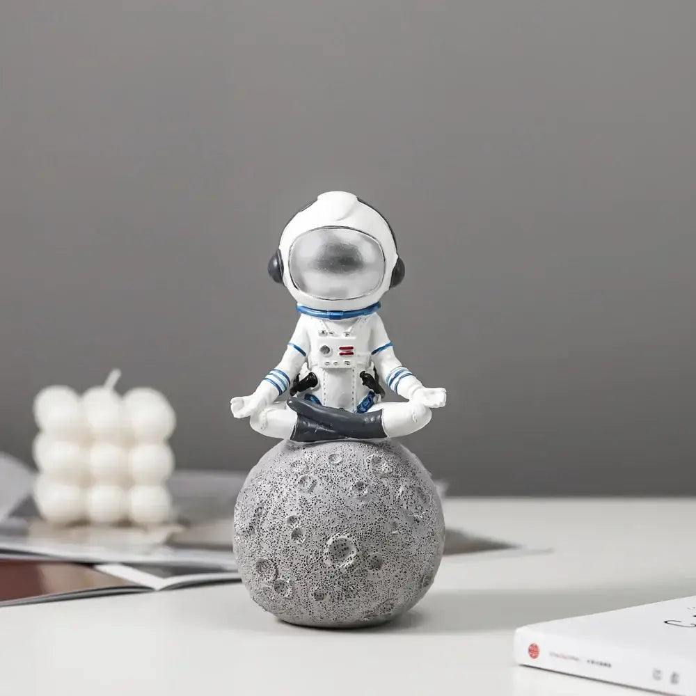 Modern white and blue decorbites astronaut resin figurines sitting in meditation on textured gray moon base for living room decor