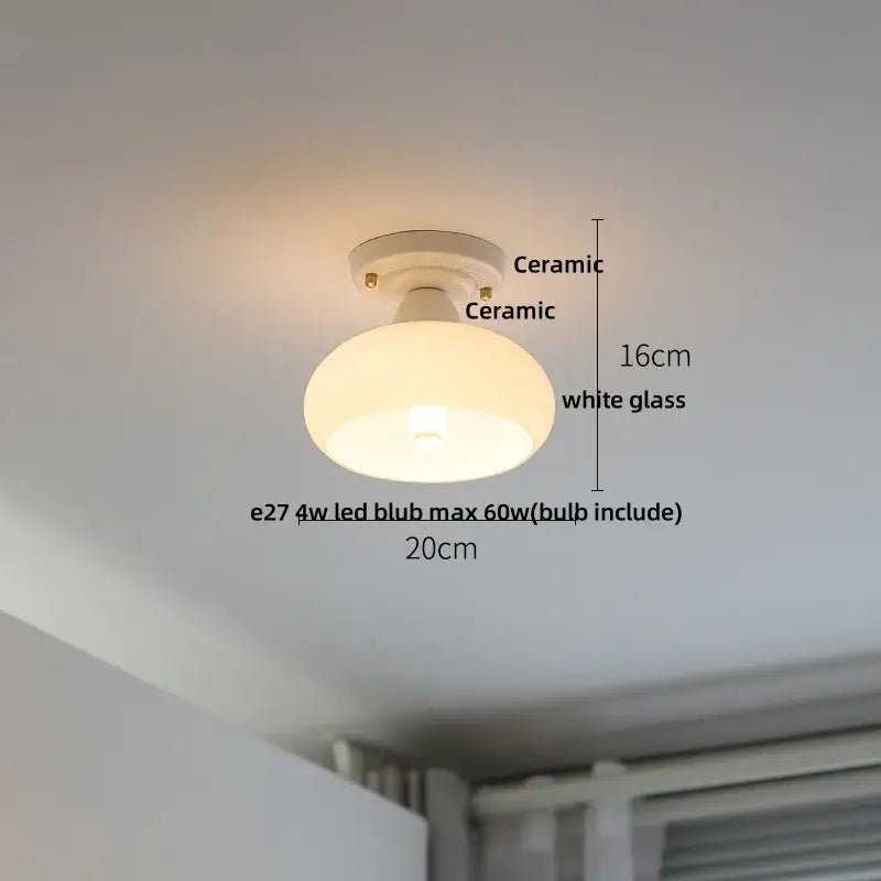 A sleek modern white and brass ceramic led ceiling lamp with a white glass shade for bedroom lighting
