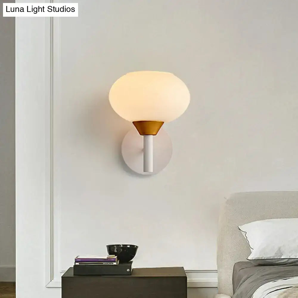 Modern wall sconce with a brass-colored conical base white stem and opal glass globe for 220v-240v bedroom lighting