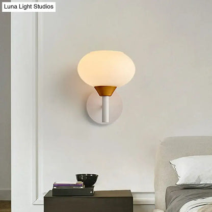 Modern wall sconce with a brass-colored conical base white stem and opal glass globe for 220v-240v bedroom lighting