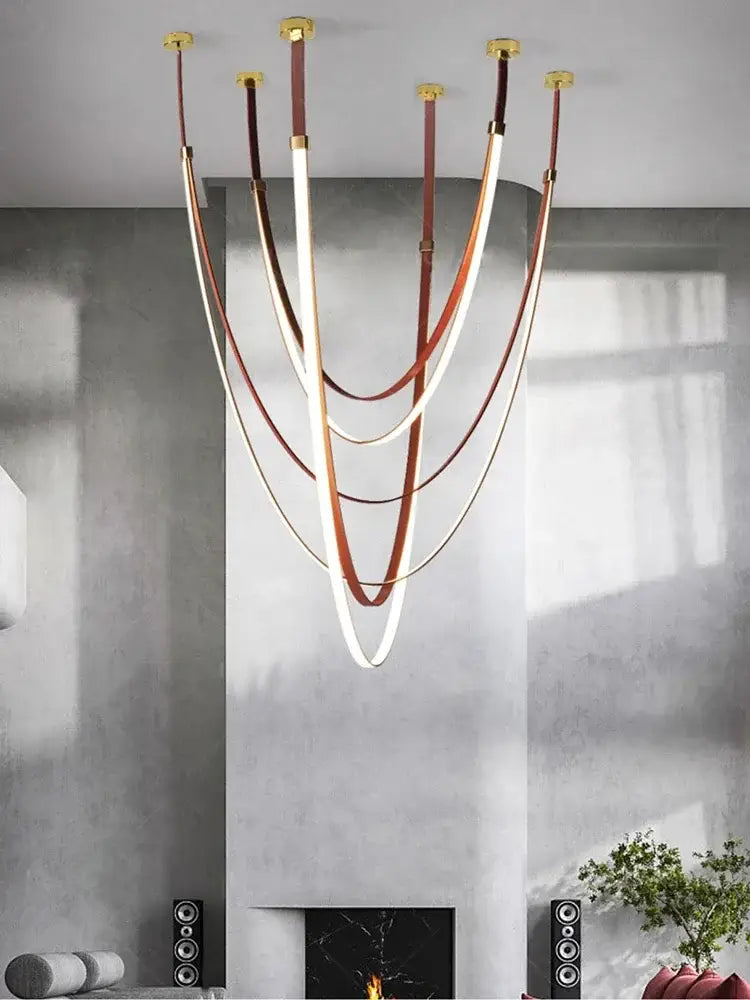 Modern white and brown leather chandelier with curved straps and gold fixtures as a belt pendant light for dining room