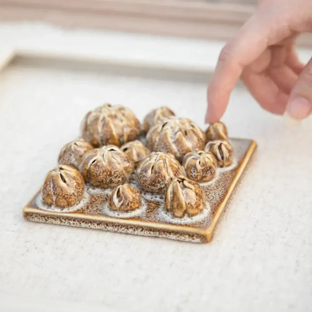 A modern white bud ceramic wall décor pendant with brown ceramic pumpkin figurines arranged on a beige tray
