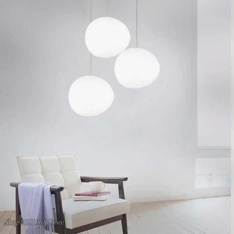 Three minimalist white spherical glass pendant lights cascade from the ceiling for modern dining room lighting