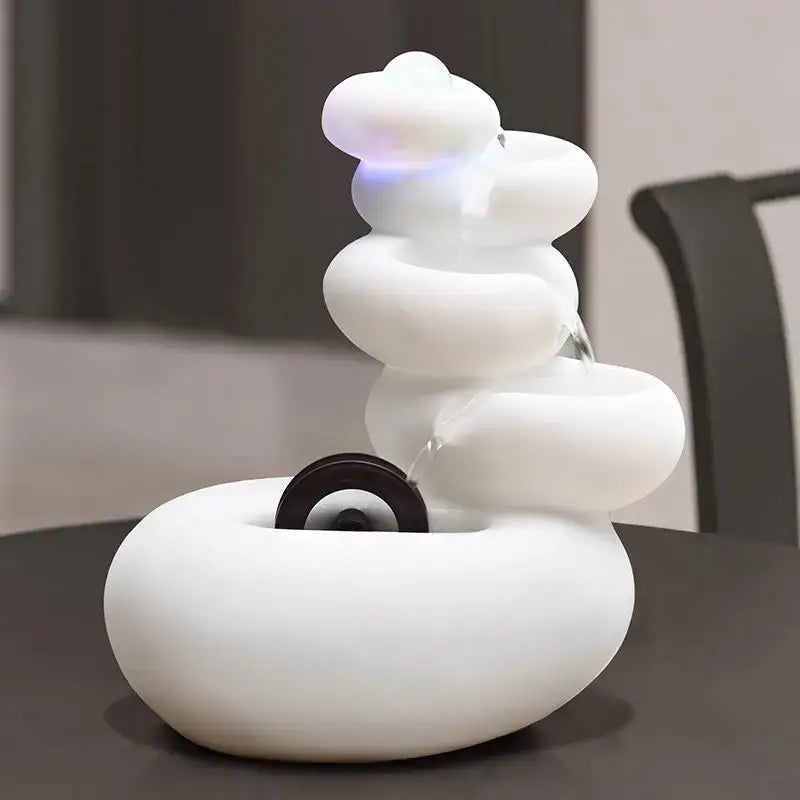 Modern white ceramic circulating water fountain with smooth stacked stone design and glowing blue light for living room decorbites circulating water fountain