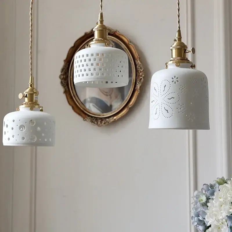 Three white ceramic flower pendant lamps with brass fixtures and decorative perforated patterns for kitchen led lighting