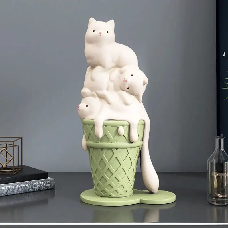 A charming white ceramic cream cat sculpture with three kittens stacked on a mint green ice cream cone for decor