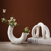 Modern white ceramic infinity symbol vase with curved textured design holding delicate white flowers decorbites infinity