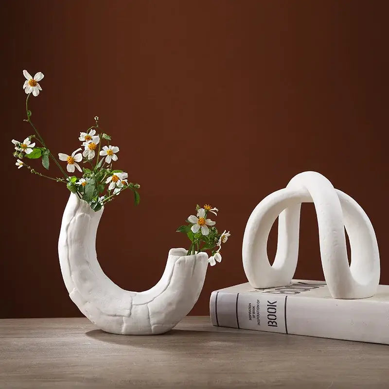 Modern white ceramic infinity symbol vase with curved textured design holding delicate white flowers decorbites infinity