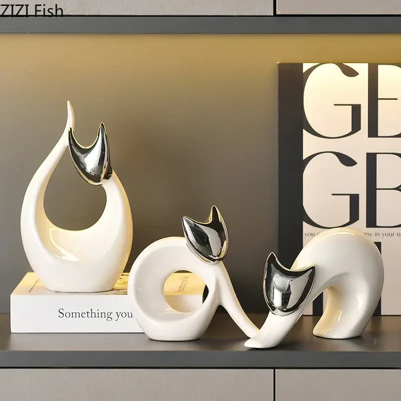 Modern white ceramic kitten statue with glossy bodies and reflective silver ears displayed on a shelf for decor