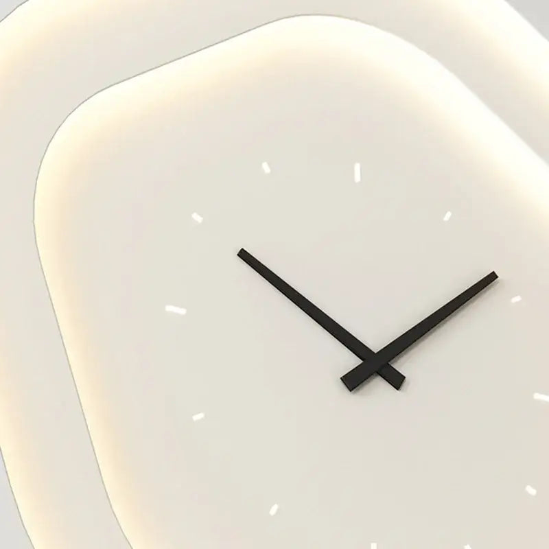 Modern minimalist wall clock with soft white rounded square face and sleek black hands paired with led wall lamp
