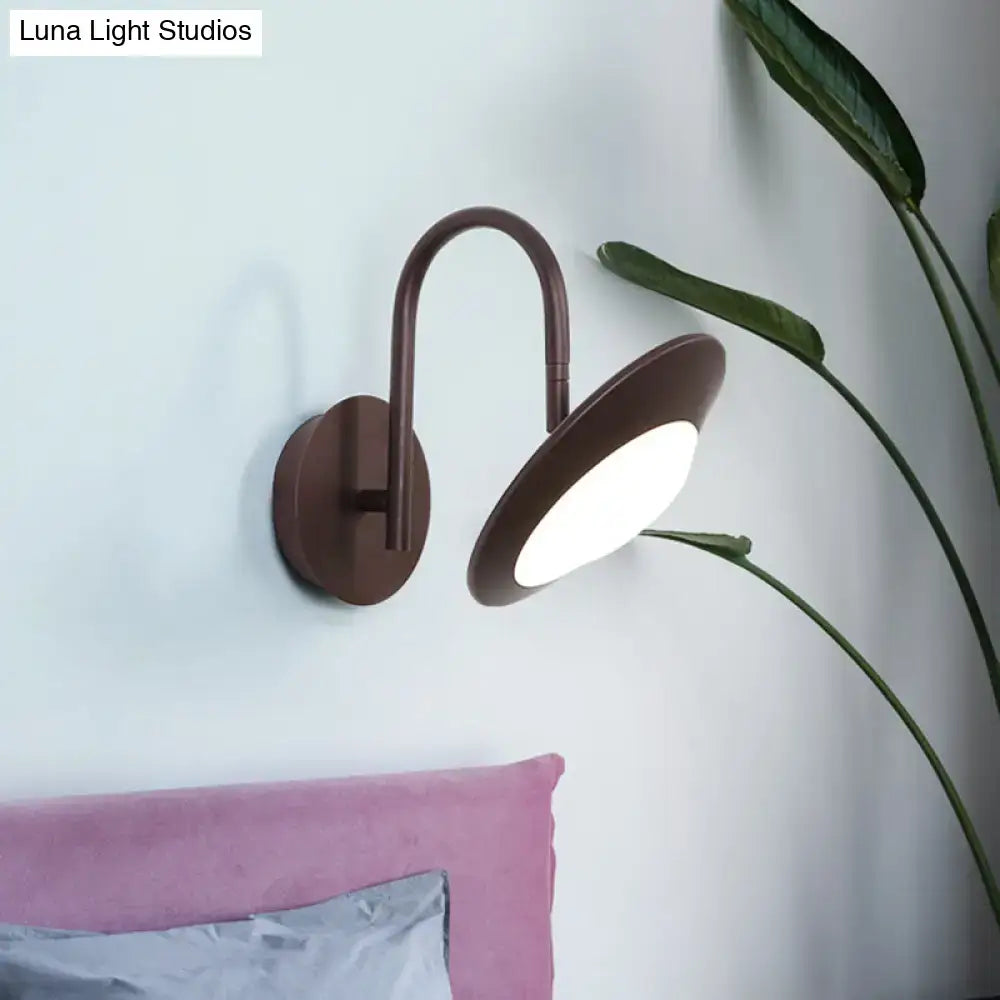 Brown metallic wall sconce lamp with curved arm and circular fixture for modern white and coffee bedroom led lighting
