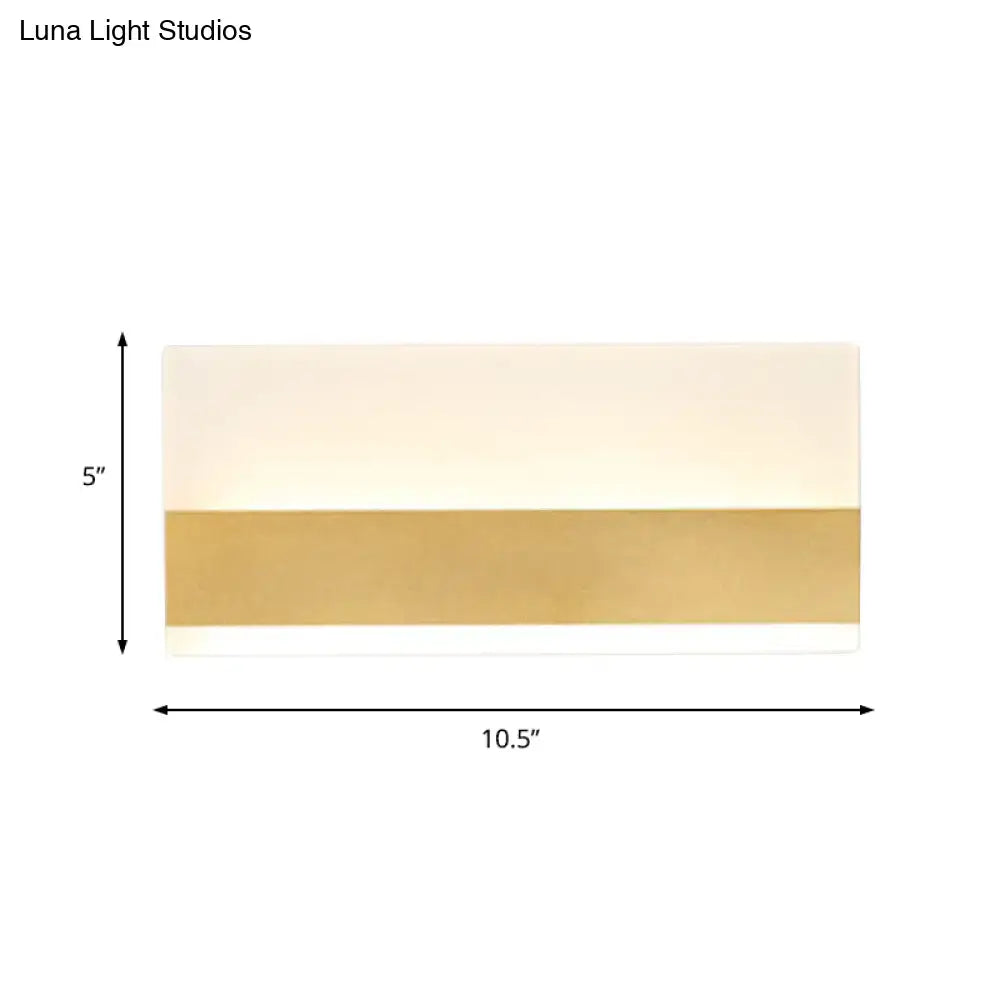 Modern white cuboid design wall sconce with polished gold band and off-white upper section emitting white warm light