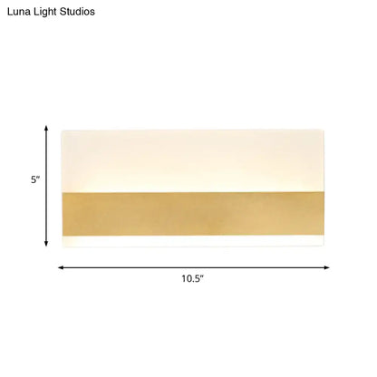 Modern white cuboid design wall sconce with polished gold band and off-white upper section emitting white warm light