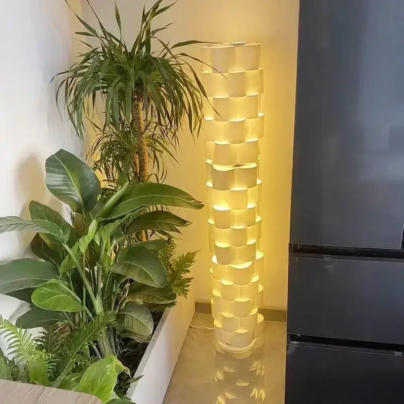 Modern white cylindrical vertical floor lamp with stacked translucent segments emitting warm yellow glow for living room