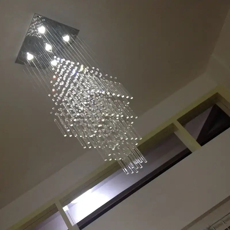 A modern white decorbites crystal ceiling chandelier with clear glass prisms and a sleek square metallic fixture for living room