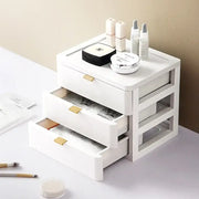 Modern white plastic decorbites desktop organizer drawer with three gold handles topped with cosmetic items including chanel compact