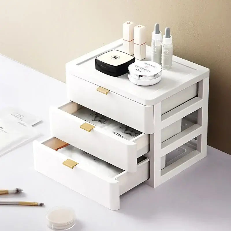 Modern white plastic decorbites desktop organizer drawer with three gold handles topped with cosmetic items including chanel compact