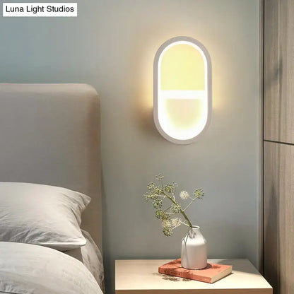 Modern white elliptical led wall lamp with a sleek frame and soft warm light for bedroom use as a wall sconce