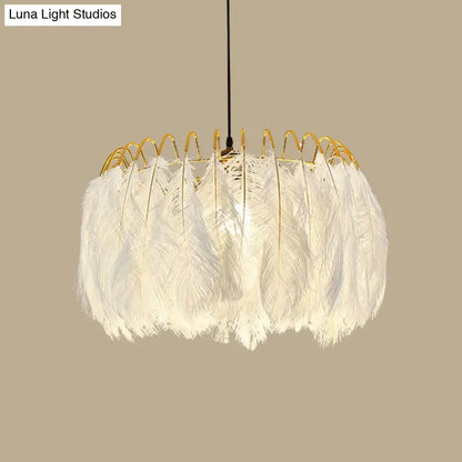 Modern white feather chandelier with a gold-toned metal frame designed as a living room pendant light
