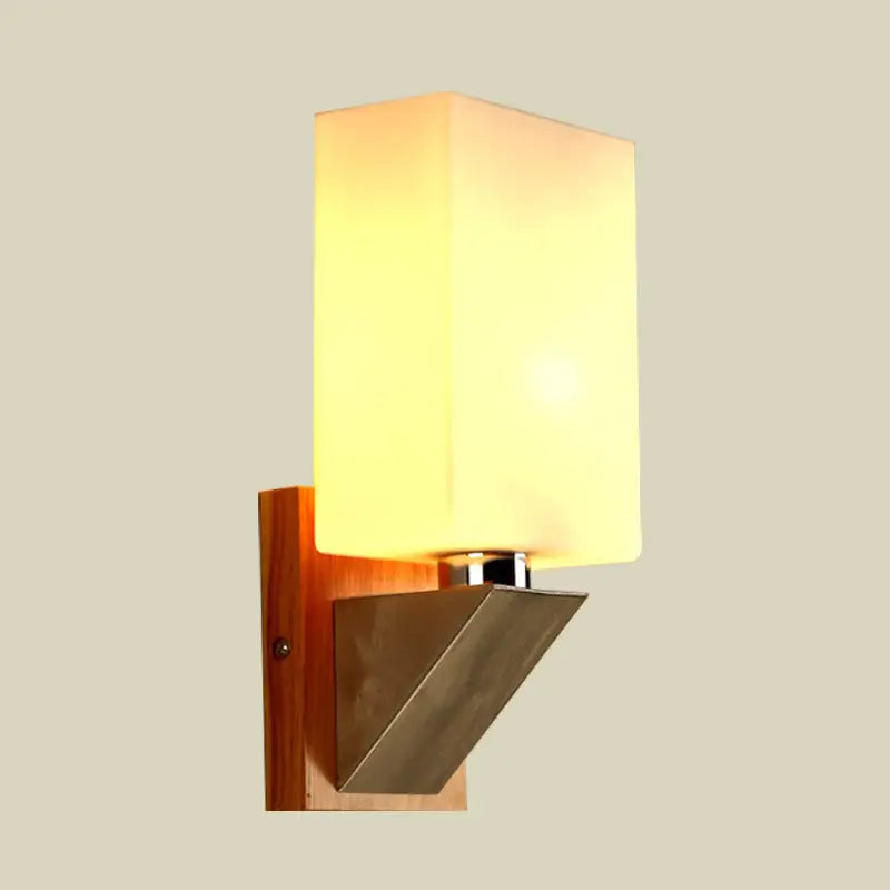 Modern wall lamp with warm-toned white frosted glass, wooden base, and metal base triangle accent for bedroom use
