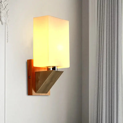 Modern warm-toned wall lamp with white frosted glass shade and wooden base with metal accents for bedroom use