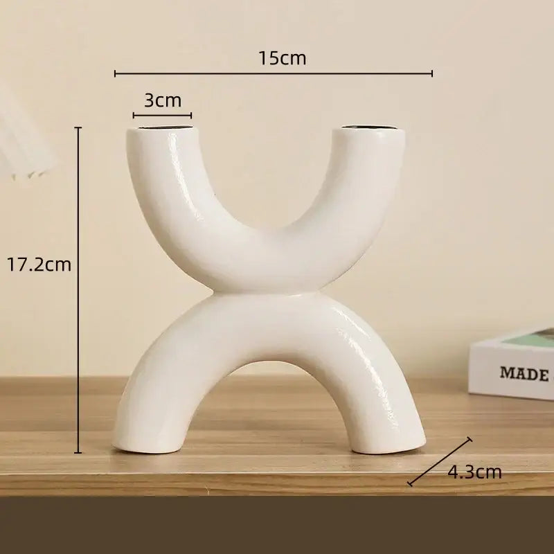 Modern white geometric ceramic candle holder with abstract u-shaped design and two curved openings for decorbites decor