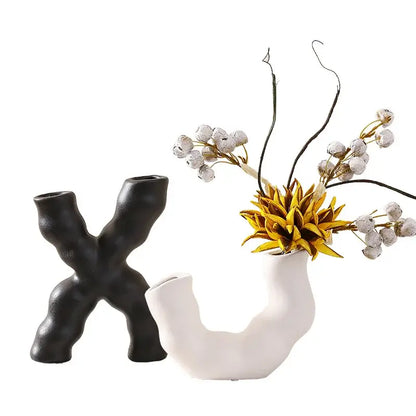 Modern white geometric ceramic flower vase with organic curved form holding golden yellow artificial flower and white berries