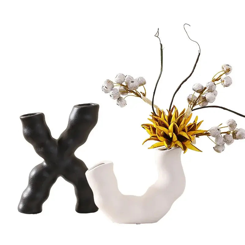 Modern white geometric ceramic flower vase with organic curved form holding golden yellow artificial flower and white berries