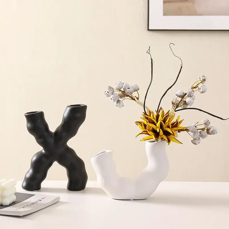 Modern white geometric ceramic flower vase with organic curved form holding yellow flower and frosted white berries decorbites