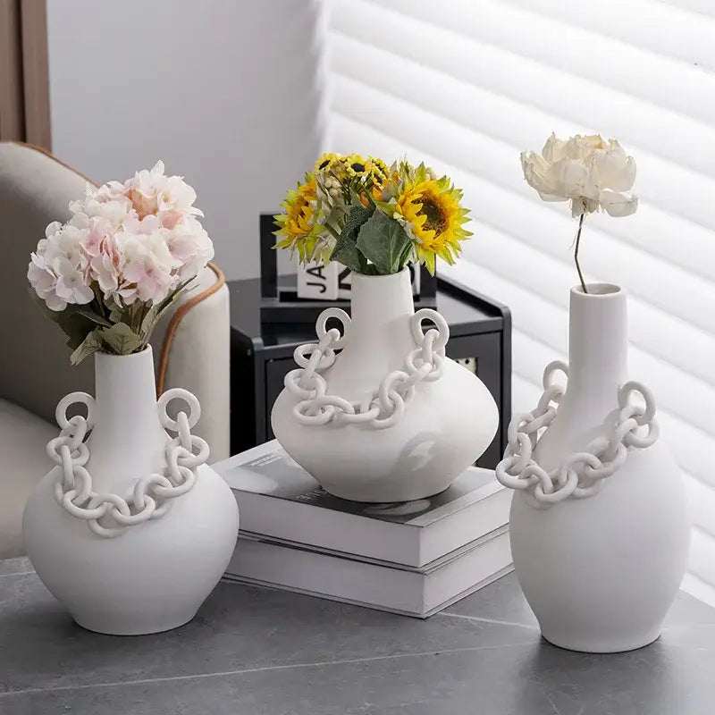 Three white ceramic geometric chain porcelain vases with sculpted chain detail holding floral decorbites geometric chain decor
