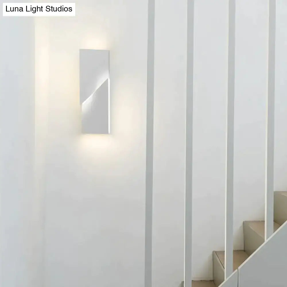 Modern white rectangular wall sconce with sleek minimalist geometric design illuminating a living room art space