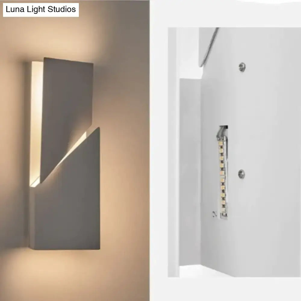 Modern gray wall sconce with sleek angular design emitting warm ambient lighting for living room illumination