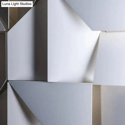 Modern white geometric wall lamp with smooth matte white and metallic surfaces in an angular living room design