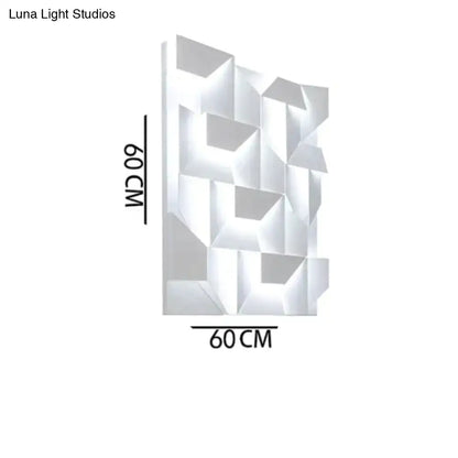 Modern white geometric wall lamp with faceted design illuminated as living room art panel