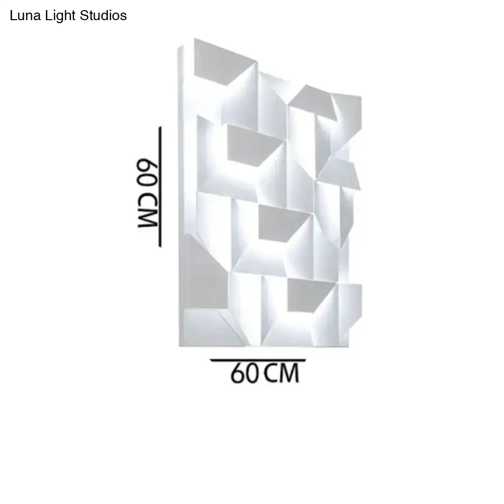 Modern white geometric wall lamp with faceted design illuminating living room as decorative art panel