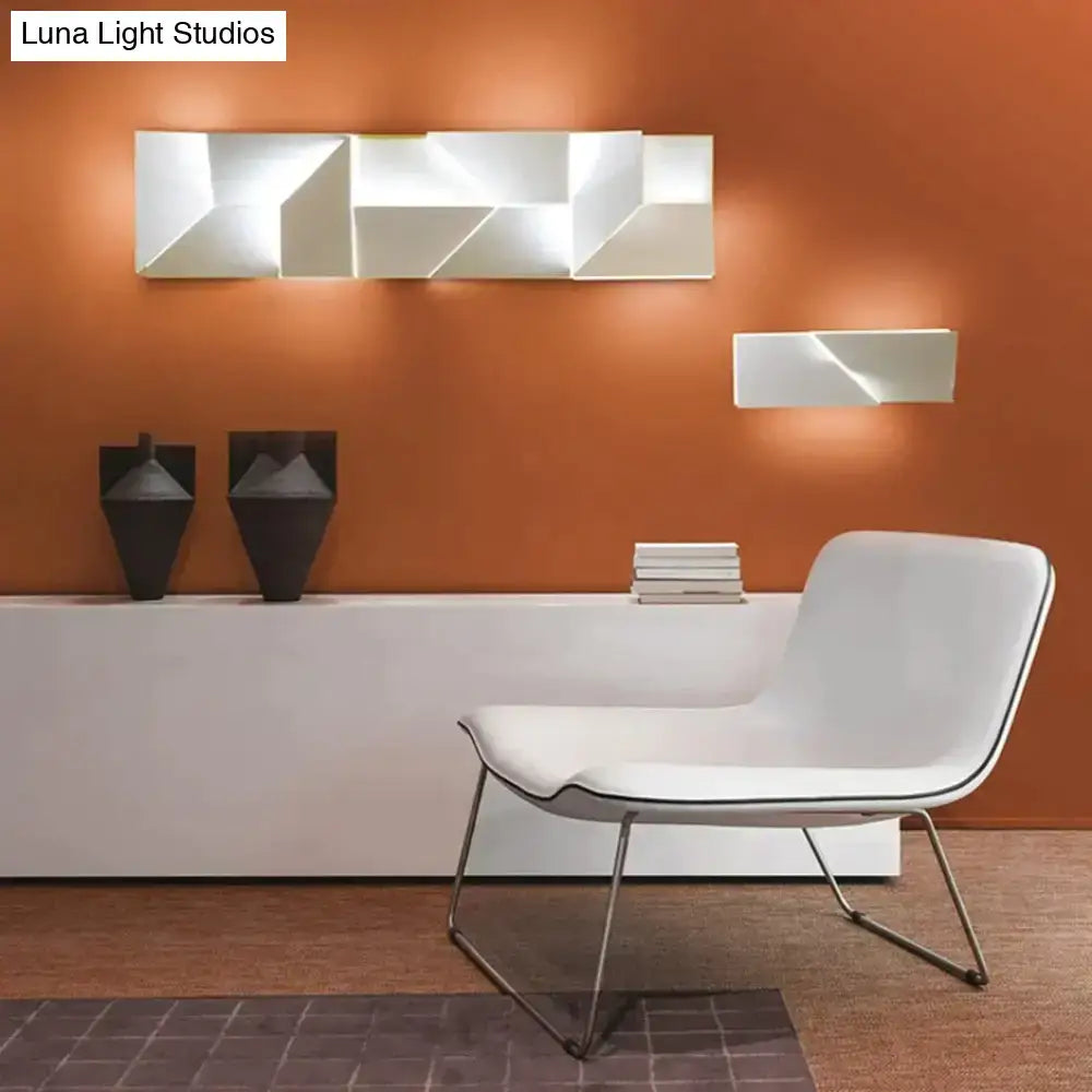 Modern white geometric wall lamp with angular faceted design illuminating a living room as art lighting