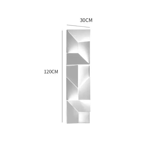 A modern white geometric wall lamp with a metallic finish illuminated in a living room setting