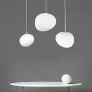 Three white glass ball led pendant lights with frosted shades hang above a marble table modern decorbites pendant light