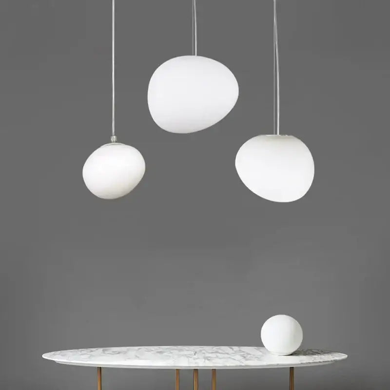Three white glass ball led pendant lights with frosted shades hang above a marble table modern decorbites pendant light