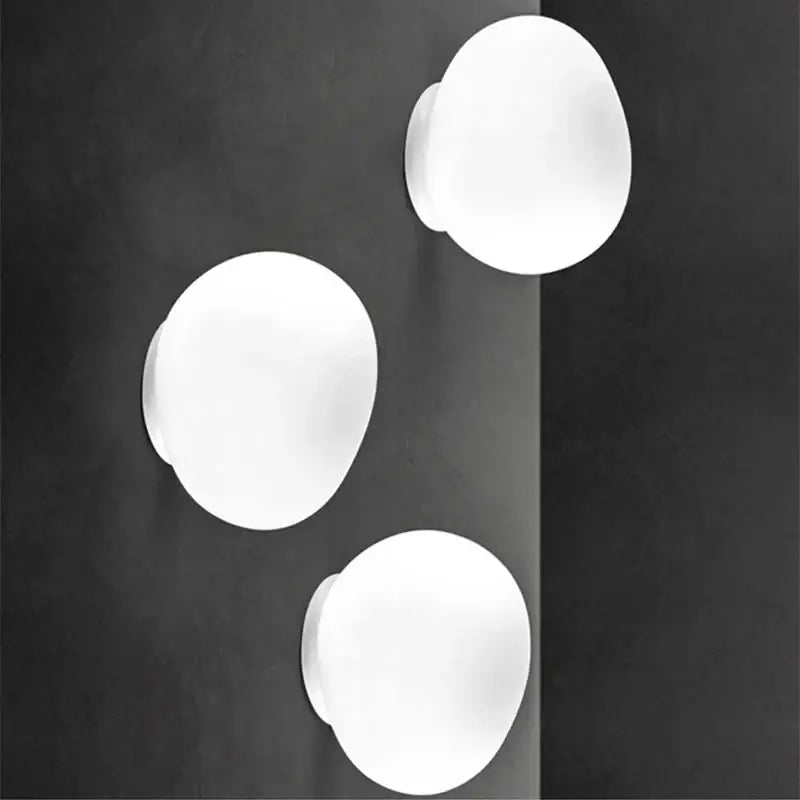 Three minimalist white glass egg wall sconces with a smooth matte finish modern wall lamp for bedroom lighting