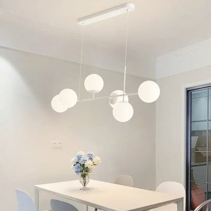 Modern white glass pendant chandelier light set featuring spherical frosted glass shades for dining room lighting