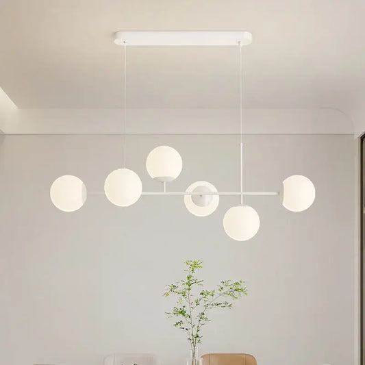 Modern white glass pendant chandelier light set with spherical globes and minimalist metal frame for dining room