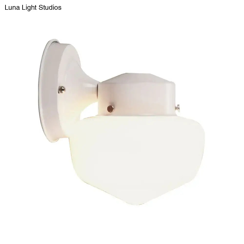 Modern white glass sconce light with frosted glass shade and painted metal housing near black white mirror