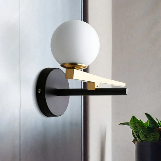 Modern white glass sphere wall light with gold accents and black base single light for bedroom use