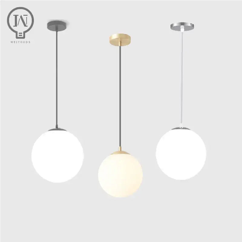 Three modern pendant lights with white globe shades and minimalist black gold and silver metal fixtures for kitchen dining room