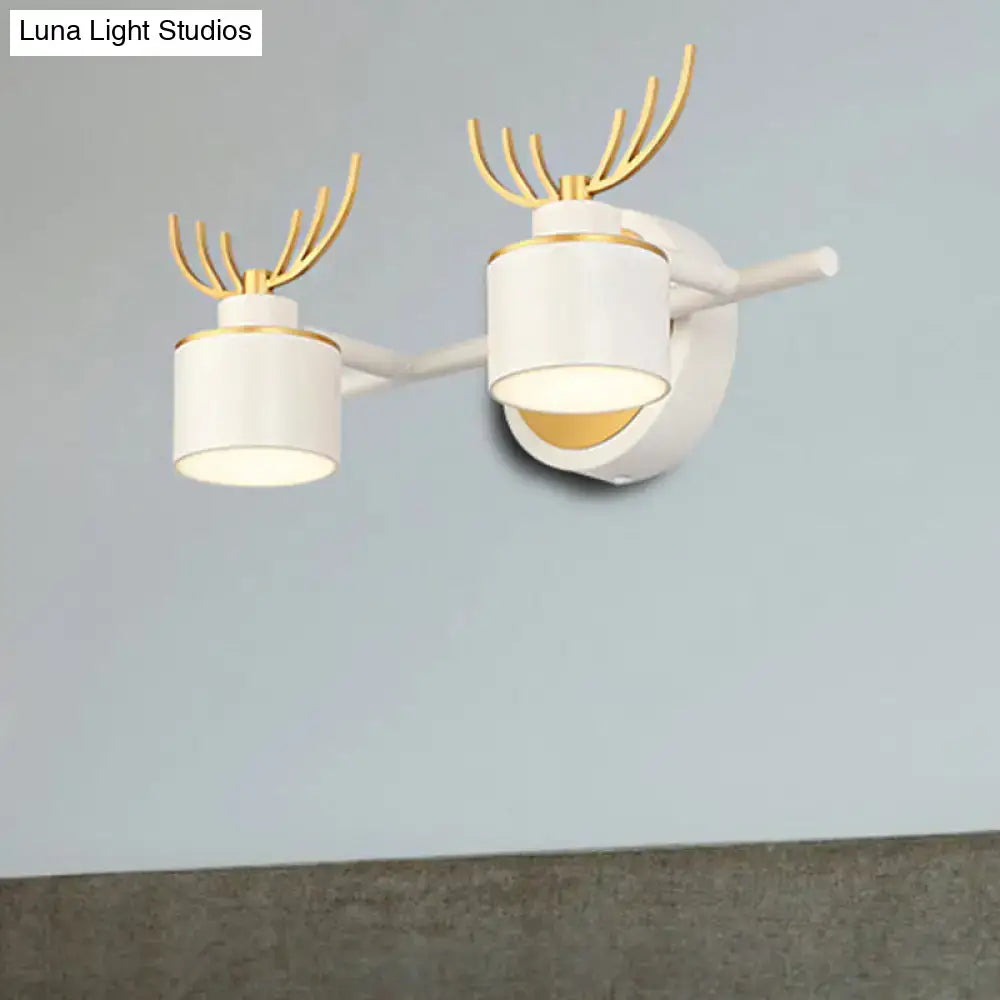 Modern white and gold antler wall light fixture with cylindrical shades designed for bathroom vanity lighting