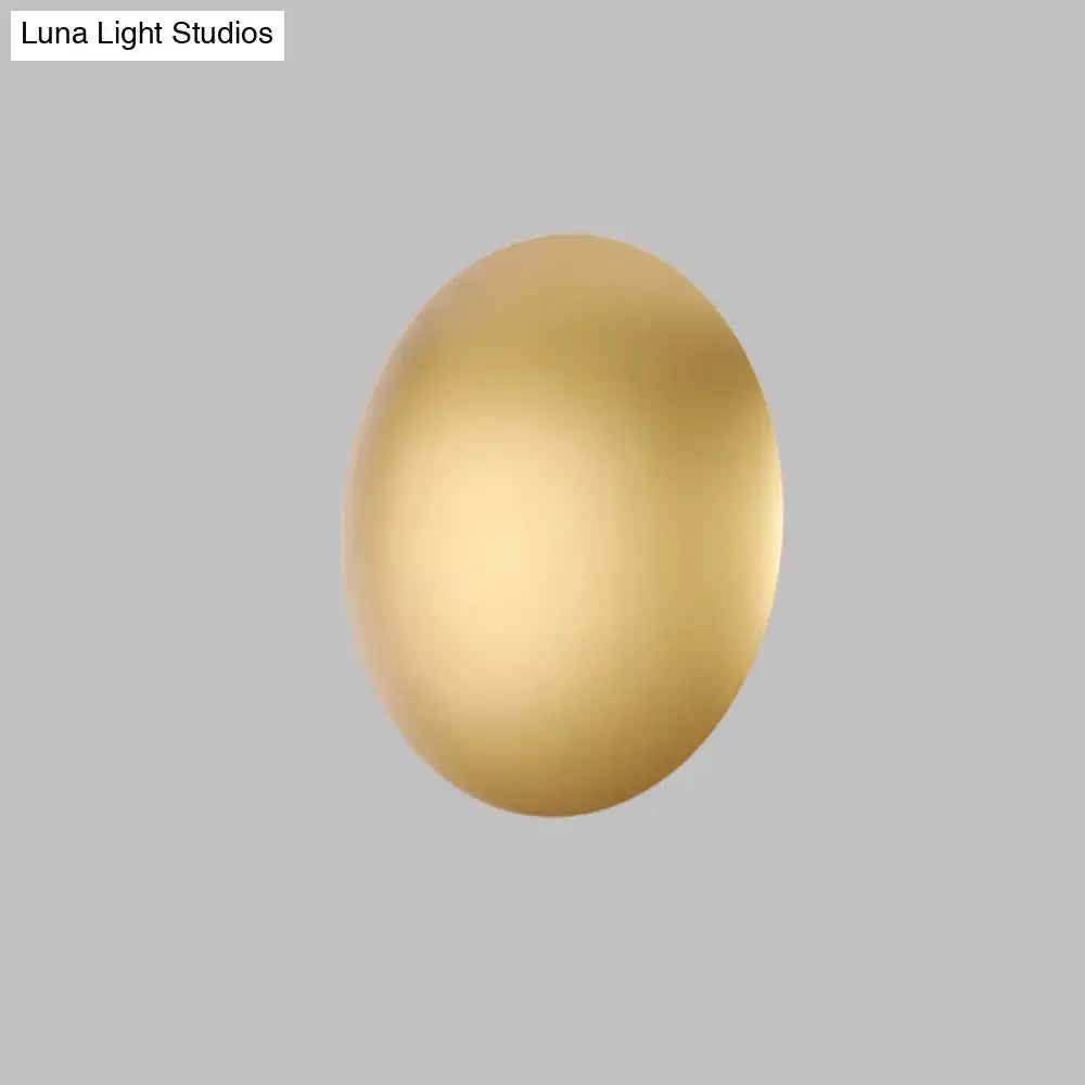 A sleek oval white gold wall light with warm white LED illumination ideal for modern bedroom lighting